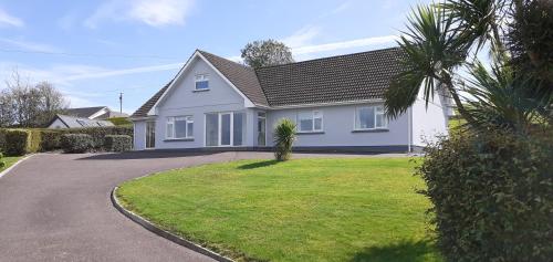 a white house with a green lawn in front of it at Joan B+B in Clonakilty