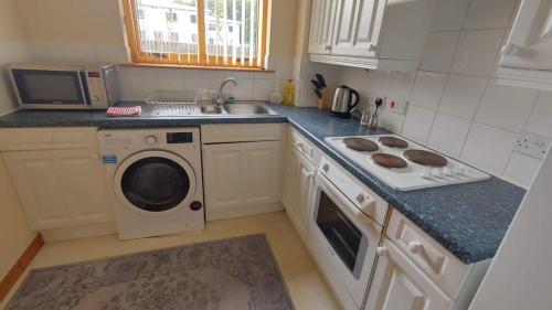 a kitchen with a sink and a washing machine at Superb 2 Bedroom Flat in Inverness
