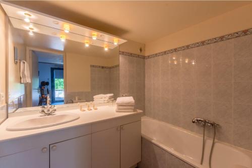 a bathroom with a sink and a mirror and a tub at Auberge de Saugras in Argelliers