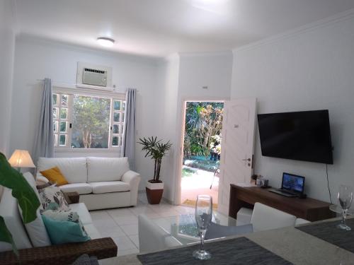 a living room with a white couch and a tv at Casa & Jardim Riviera in Riviera de São Lourenço