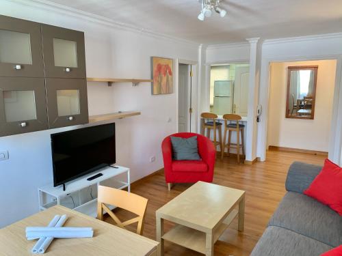 Apartamentos Bruja في سانتا كروث دي تينيريفه: غرفة معيشة مع أريكة وتلفزيون وطاولة