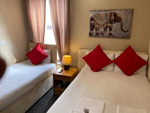 two beds with red pillows in a room at Fortuna House Hotel in Blackpool