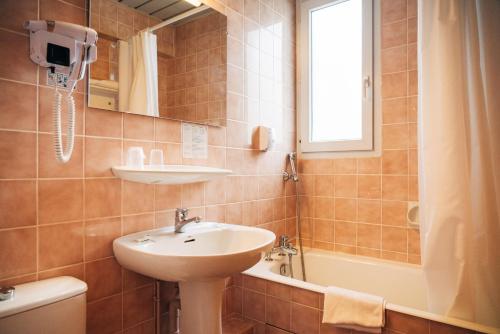 a bathroom with a sink and a bath tub at Hôtel du Soleil Levant in Argelès-Gazost