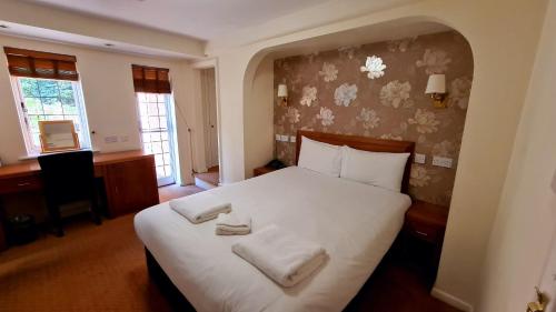 a bedroom with a bed with two towels on it at Farnham House Hotel in Farnham