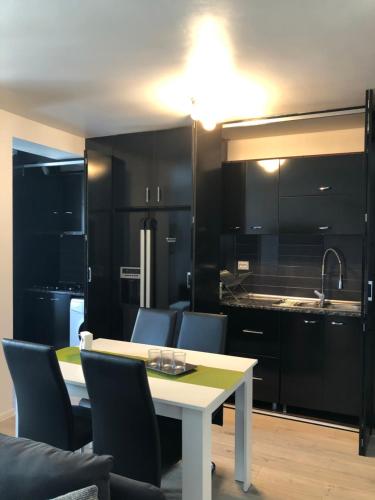 uma cozinha com armários pretos e uma mesa e cadeiras brancas em Open Space UltraCentral em Piteşti