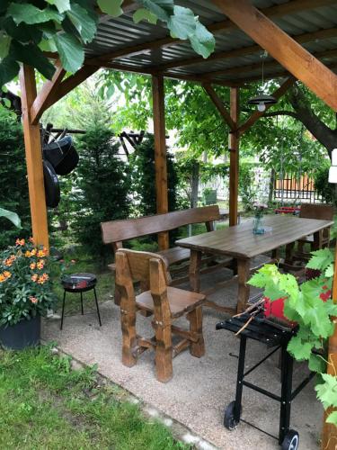 a picnic table and bench under a wooden gazebo at Levendula Apartmanház in Badacsonytomaj