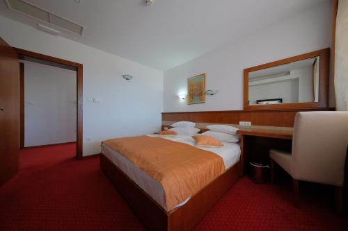 a bedroom with a bed with a desk and a mirror at Motel Mujanic Sarajevo in Sarajevo