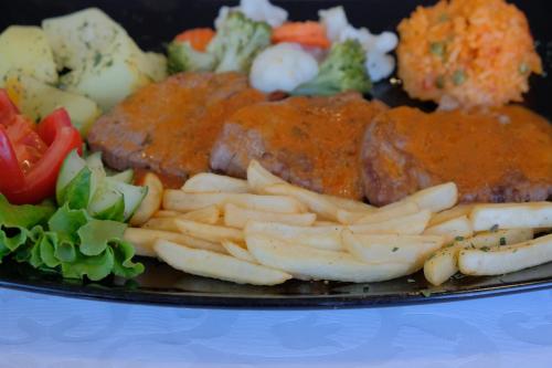 a plate of food with meat and fries and vegetables at Motel Mujanic Sarajevo in Sarajevo