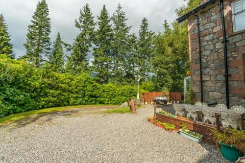 a stone house with a bench in the yard at Foyers Bay Country House in Foyers