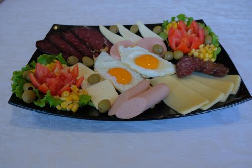 a plate of food with eggs meats and vegetables at Motel Mujanic Sarajevo in Sarajevo