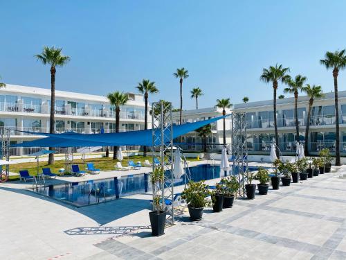 a swimming pool with palm trees and a building at Lysithea Hotel in Larnaka