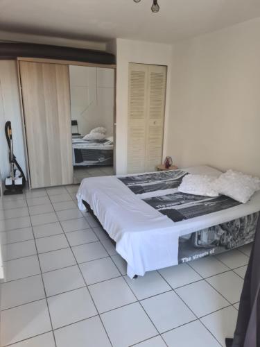 a bedroom with a large bed and a tiled floor at T2 CARRY LE ROUET CENTRE VILLE PROCHE DE LA MER in Carry-le-Rouet