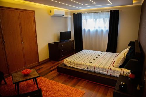 a bedroom with a bed and a window with a television at Snooker House in Ponta Delgada