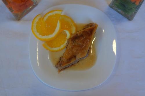 a white plate with a piece of fish and orange slices at Motel Mujanic Sarajevo in Sarajevo