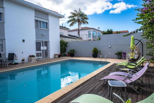 a swimming pool with chairs and a house at Snooker House in Ponta Delgada
