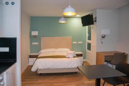 a bedroom with a bed and a tv and a table at Aparthotel Essenzia de Castilla in Aranda de Duero