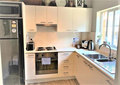 Una cocina con gabinetes blancos y un refrigerador de acero inoxidable. en Top Mosman Location, en Sídney