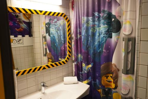 a bathroom with a shower curtain, a toilet, and a sink at Hotel Legoland in Billund