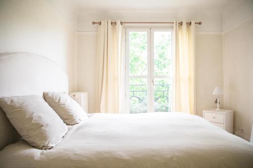 una camera bianca con un letto e una finestra di Romantic Nest a Parigi