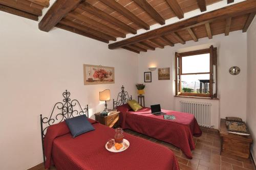 een kamer met 2 bedden met rode lakens en een raam bij Casa Emilia in Chiusdino