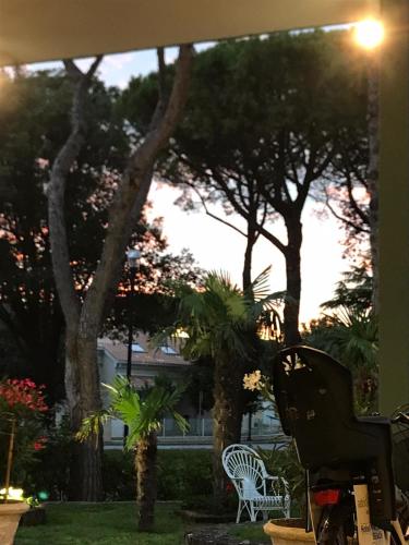 a patio with two white chairs and trees at Hotel Palm Beach in Lido di Jesolo