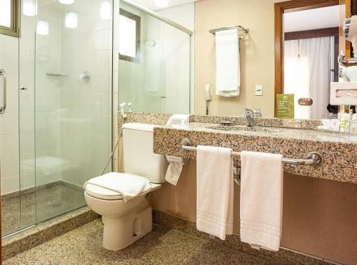 a bathroom with a toilet and a glass shower at Mercure Belo Horizonte Lourdes in Belo Horizonte