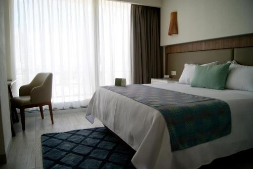 a hotel room with a large bed and a chair at Hotel Velvet Plaza in Guadalajara