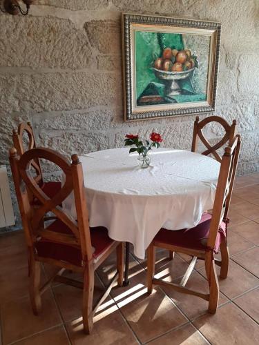 a table with a vase of flowers and a bowl of fruit at Os Areeiros Turismo Rural & Bodega in Santa Cristina de Cobres
