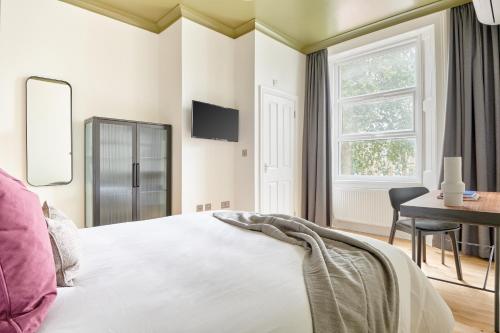倫敦的住宿－Sonder Camden Road，一间卧室配有一张床、一张书桌和一个窗户。