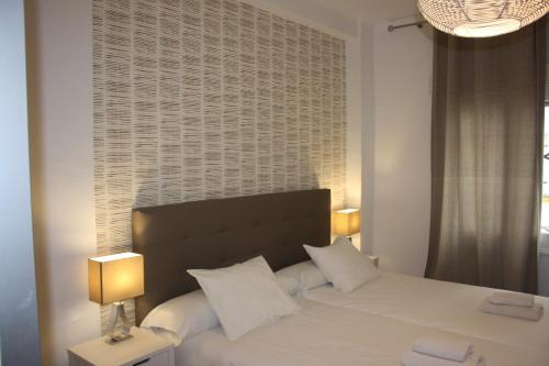 Un dormitorio con una cama con almohadas blancas y una ventana en Coliseo Premium Apartment, en Sevilla