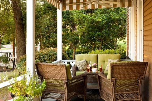 a porch with two wicker chairs and a couch at Devereaux Shields House in Natchez