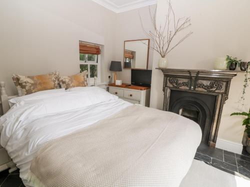 a bedroom with a white bed and a fireplace at Yew Tree Cottage in York