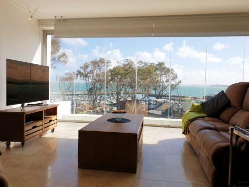 uma sala de estar com um sofá e uma grande janela em 24 Gordonia, Sleeps 7, Beach Front condo - Load-shedding friendly with Solar Power and battery backup em Gordonʼs Bay