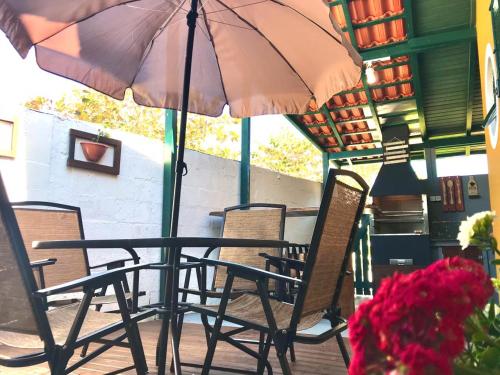a table and chairs with an umbrella on a patio at Casa Chale 10 Florianópolis in Florianópolis