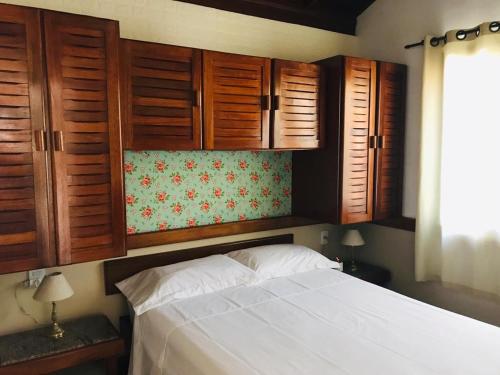 Casa Chale 10 Florianópolis في فلوريانوبوليس: غرفة نوم بها دواليب خشبية وسرير ابيض