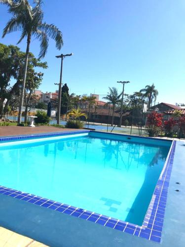 a large blue swimming pool with a palm tree at Casa Chale 10 Florianópolis in Florianópolis