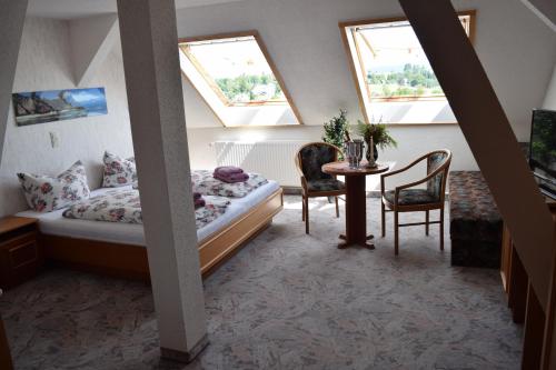 a bedroom with a bed and a table and chairs at Hotel Carola in Schönheide