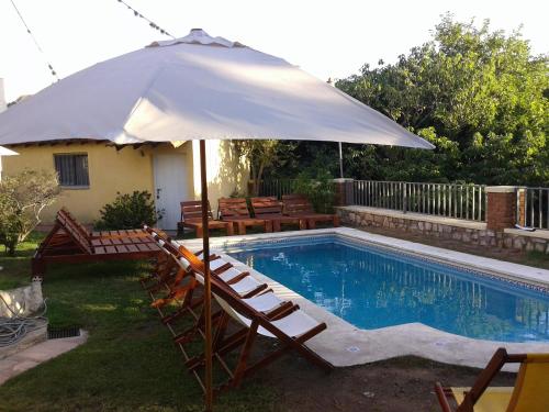 an umbrella and chairs next to a swimming pool at Hotel El Nogal in La Falda