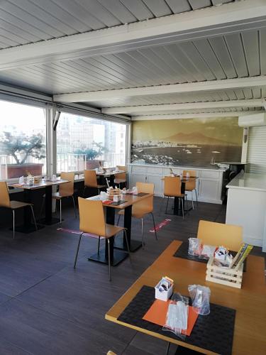 a dining room with tables and chairs and windows at Airone Hotel in Naples