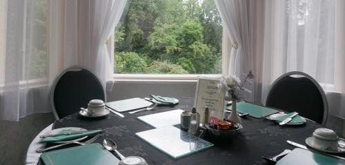 a dining room table with chairs and a large window at Ashwood Hotel in Preston