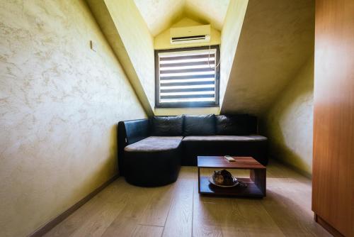 a living room with a black couch and a window at ATOS Srebrno jezero - Villa and Restaurant in Veliko Gradište