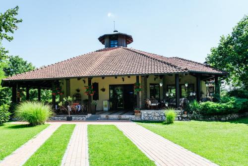 a large yellow house with a clock tower on top at ATOS Srebrno jezero - Villa and Restaurant in Veliko Gradište