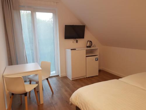 Kleines Zimmer mit einem Tisch, einem Bett und einem TV. in der Unterkunft Pensjonat Orle Gniazdo in Jelenia Góra