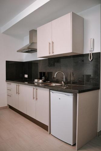 a kitchen with white cabinets and a sink at DanySer Suites Vacacionales in Agulo