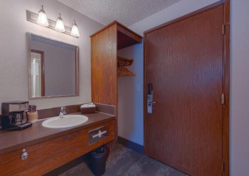 uma casa de banho com um lavatório, um espelho e uma porta de madeira em Silver Inn em Kellogg