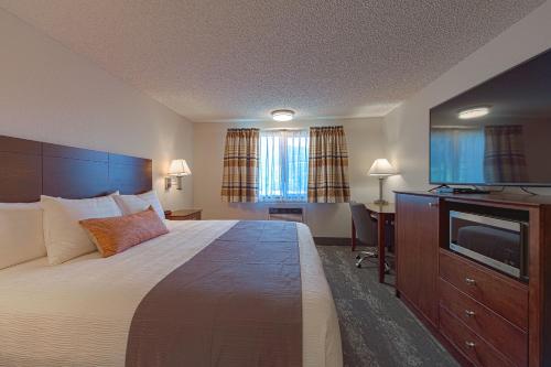 ein Hotelzimmer mit einem Bett und einem Flachbild-TV in der Unterkunft Silver Inn in Kellogg