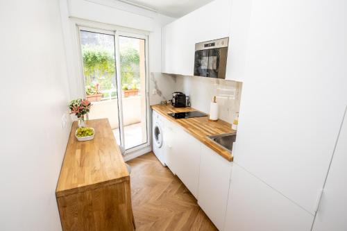 una cucina con armadietti bianchi e un bancone in legno di Fabuleux Studio a Beausoleil