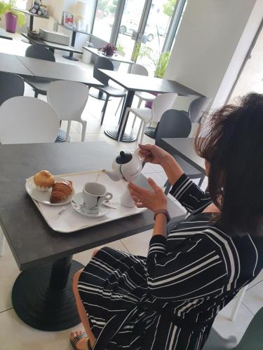 a woman sitting at a table with a cup of coffee at BRIT HOTEL CONFORT NEVERS Centre Gare in Nevers