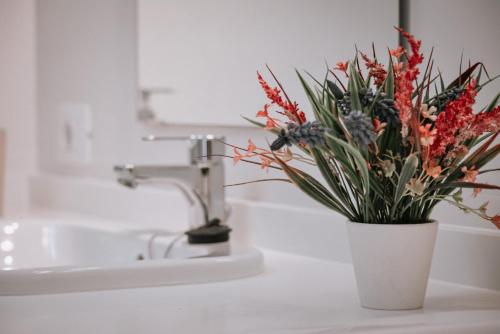 a white bathroom sink with a vase with flowers at DanySer Suites Vacacionales in Agulo