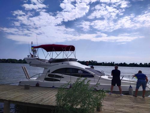 Zwei Männer stehen auf einem Boot an einem Dock. in der Unterkunft Kambodzha na Dynae in Wylkowe